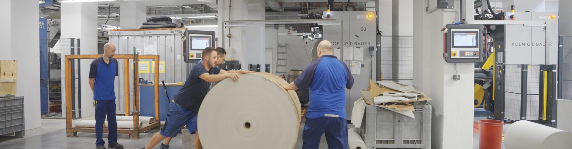 Papierrolle wird von Mitarbeitern transportiert